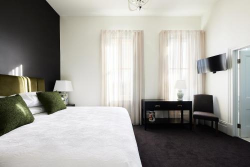 a bedroom with a white bed and a desk with a chair at The Royal Queenscliff in Queenscliff