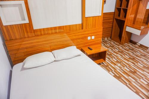 a bedroom with a white bed and wooden walls at Hotel O Atifah Homes in Sungguminasa