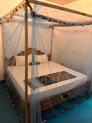 a bedroom with a canopy bed with white sheets at Yoga ShacK in Arugam Bay