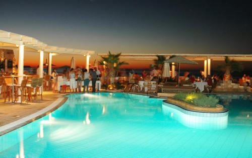 a swimming pool at a hotel with people standing around it at Parthenis Hotel & Suites in Malia
