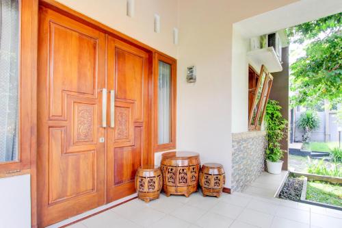 a wooden door with two drums in front of a house at Hotel O Homestay Koe Syariah in Purwokerto