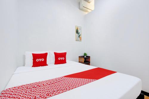 a bedroom with a white bed with red pillows at Hotel O Homestay Koe Syariah in Purwokerto