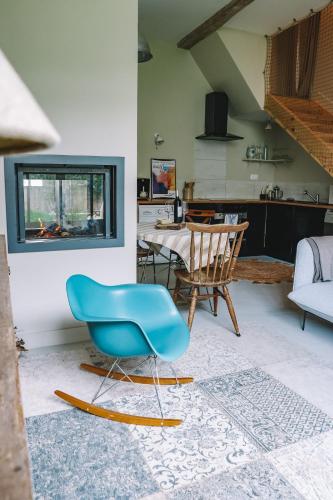 un salon avec une chaise bleue et une table dans l'établissement Ikigai Fontainebleau - Cottage, à Villiers-sous-Grez