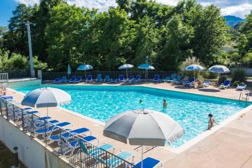 - une piscine avec des parasols et des chaises bleus et blancs dans l'établissement T3 résidence privée proche plage et piscine, à Poggio-Mezzana