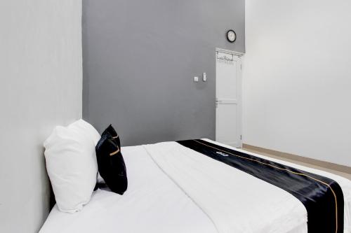a bedroom with a white bed with a black pillow at Capital O 93939 Oikodomeo Syariah in Salatiga