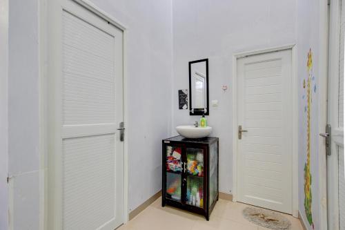 a bathroom with two white doors and a sink at Capital O 93939 Oikodomeo Syariah in Salatiga