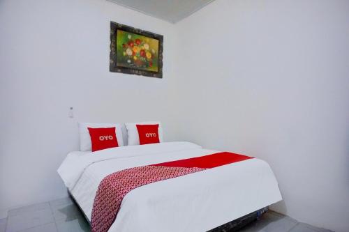 a white bedroom with a white bed with red pillows at Hotel O Family Guesthouse in Medan