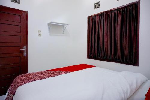 a bedroom with a white bed and a window at Hotel O Family Guesthouse in Medan