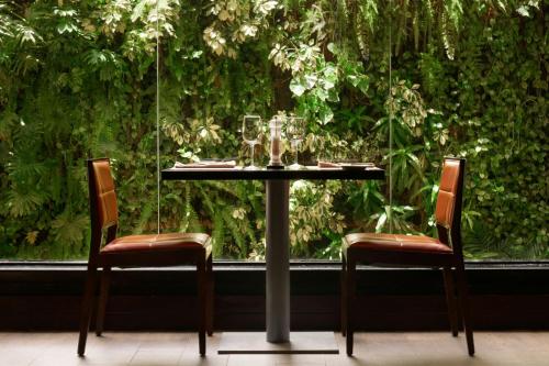 a table with two chairs and glasses on it in front of a window at Renaissance Caracas La Castellana Hotel in Caracas