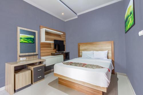 a bedroom with a large bed and a television at Belvilla Surga Pandawa Bali in Jembrana