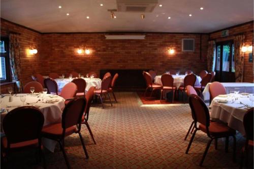 a dining room with tables and chairs with white tablecloths at OYO Blaby Westfield Hotel in Leicester
