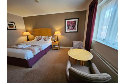 a hotel room with a bed and a table and chairs at OYO Blaby Westfield Hotel in Leicester