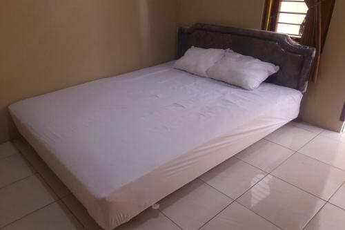 a large white bed with a pillow on it at Hotel O Kost Indra in Sungguminasa