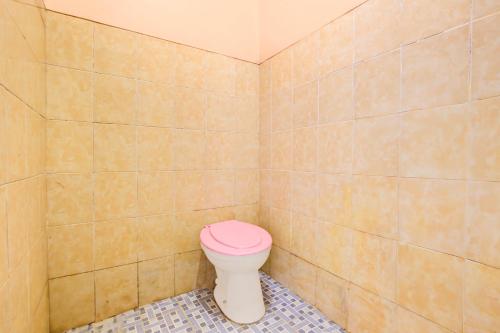 a bathroom with a toilet with a pink lid at Hotel O Homestay Baronsari in Kemadang