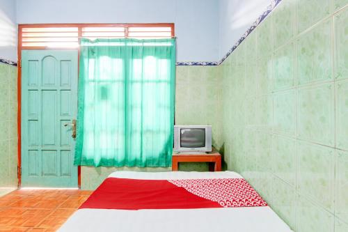 a bedroom with a bed and a tv on a table at Hotel O Homestay Baronsari in Kemadang