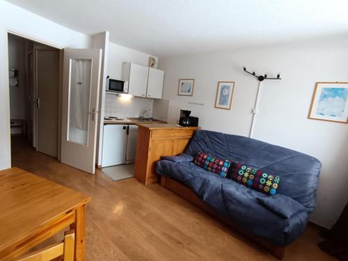 un salon avec un canapé bleu et une cuisine dans l'établissement Résidence Ferme D'augustin - Batiment D - Appartement 4/6 personnes - Skis aux pieds MAE-9154, à Montgenèvre