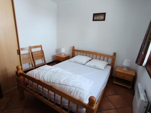 - une chambre dotée d'un lit en bois avec des draps et des oreillers blancs dans l'établissement Résidence Korossol - 3 pièces pour 6/8 personnes à 100 m des pistes MAE-9124, à Montgenèvre
