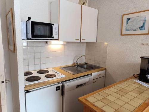 une cuisine avec une cuisinière, un évier et un micro-ondes dans l'établissement Résidence Ferme D'augustin - Batiment F - Appartement 2 pièces 4/6 personnes -Skis aux pieds MAE-9144, à Montgenèvre