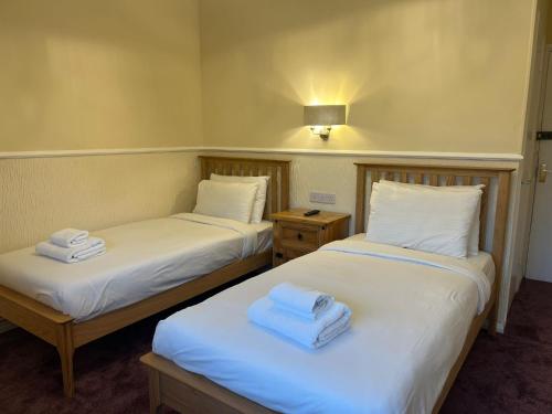two beds in a room with towels on them at Rothwell House Hotel in Kettering