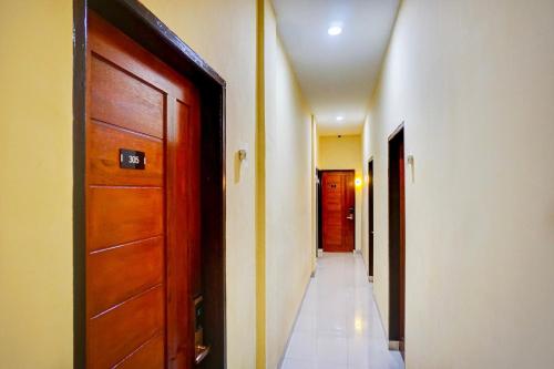 a hallway with a wooden door and a hallway with two rooms at Hotel O Helvetia Near Plaza Millenium Formerly Sunny Inn in Pulauberayan