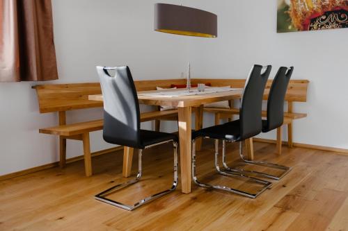 a wooden table with four black chairs around it at Kanis Appartements in Schoppernau