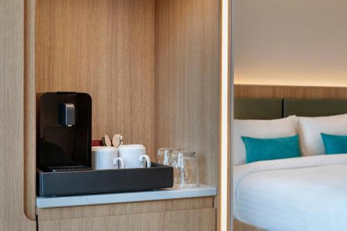 a hotel room with a coffee maker on a shelf next to a bed at Courtyard by Marriott Biel Bienne in Biel