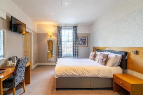 a hotel room with a bed and a desk and a desk at OYO The Red Lion Hotel in Luton