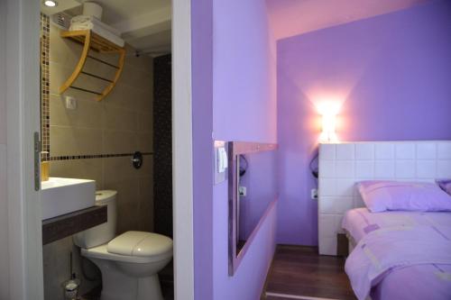 a purple bedroom with a toilet and a sink at Aloha Apartments with pool in Skopje