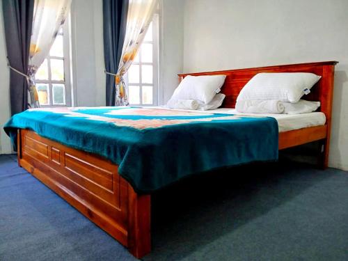 a bedroom with a large bed with a wooden headboard at Dio Green House NUWRA ELIYA in Nuwara Eliya