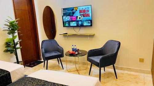 a room with two chairs and a table and a tv at Holiday Guest House Lahore in Lahore