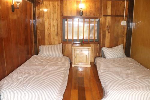 two beds in a room with wooden walls at Atash Eco Village Homestay Van Hoi in Quân Khê