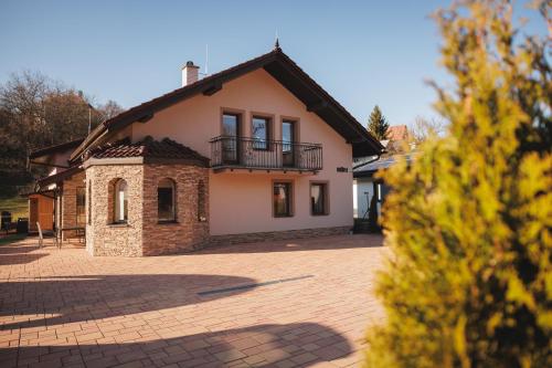 a house with a balcony and a brick driveway at Dom v stráni in Poniky