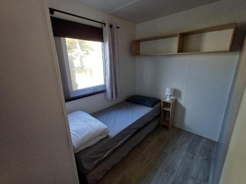 - une petite chambre avec un petit lit et une fenêtre dans l'établissement Charmant mobil-home 178, à Narbonne