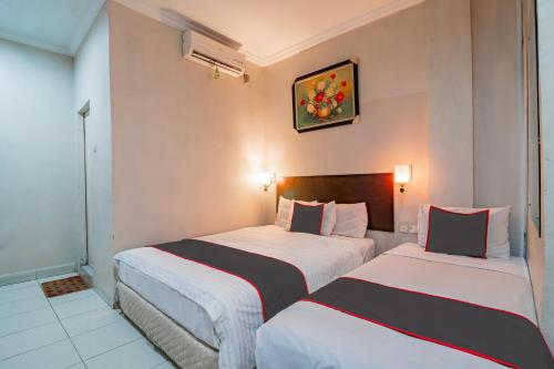 a hotel room with two beds and a picture on the wall at Collection O Pusat Kota Pekanbaru Near Mall Ska Formerly Hotel Olgaria in Pekanbaru