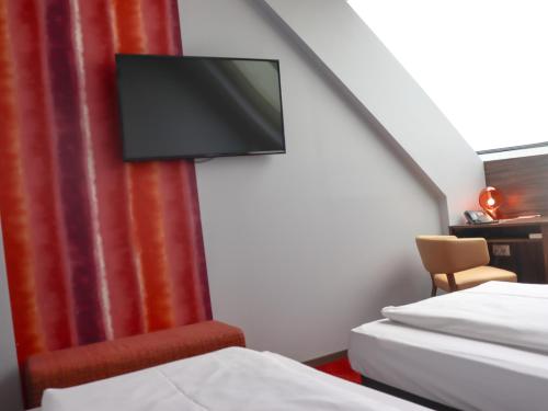 a room with two beds and a flat screen tv at Simm's Hotel - cityhotel next to Metro U3 in Vienna