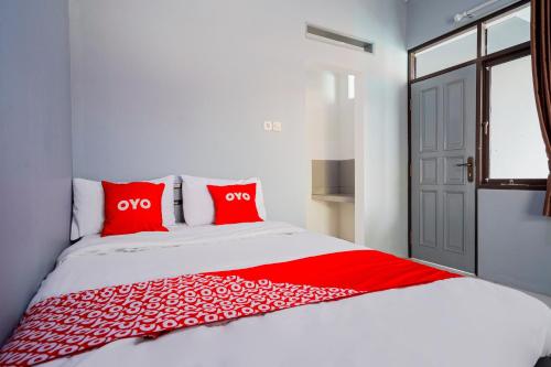 a bedroom with a bed with red pillows and a window at Hotel O Pdl Guest House Syariah in Cimahi