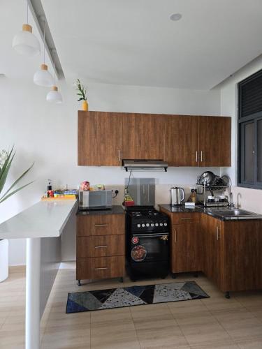 a kitchen with wooden cabinets and a stove top oven at Lakeview Condo at Pearl marina Garuga in Kagolomolo