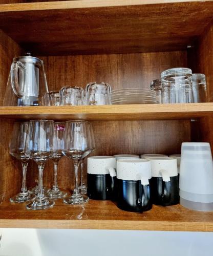a wooden shelf with glasses and wine glasses at Lakeview Condo at Pearl marina Garuga in Kagolomolo