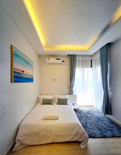 a bedroom with a large bed and a window at Lakeview Condo at Pearl marina Garuga in Kagolomolo