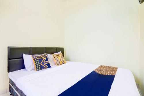 a bed with blue and white pillows on it at Hotel O Homestay Arva in Wonosari