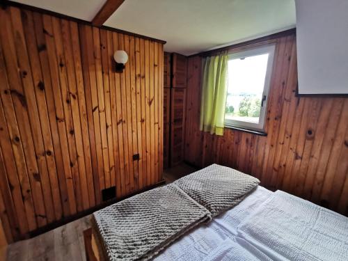 a bedroom with wooden walls and a bed with a window at Ośrodek Wypoczynkowy "U Kulasa" in Warchały