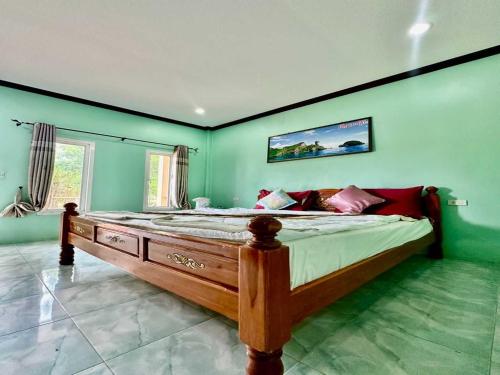 una camera da letto con un letto grande con pareti verdi di OYO 75515 Sairung Farmstay a Ban Na Pong