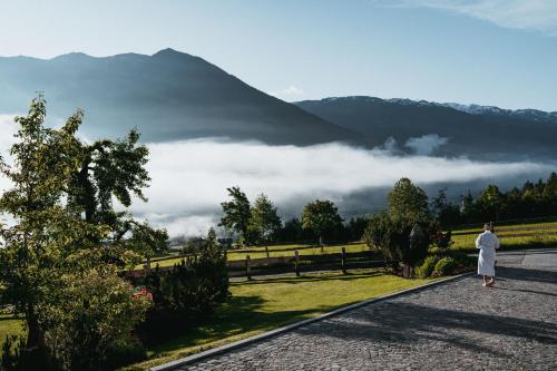a woman walking down a road with a view of a mountain at ASTER Boutique Hotel & Chalets in Fügenberg