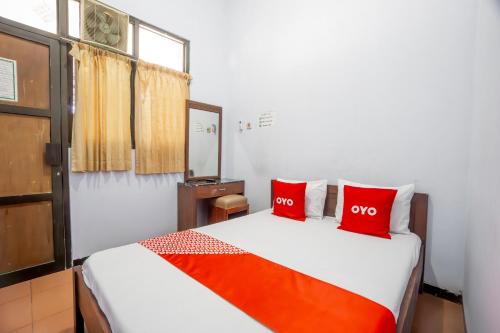 a bedroom with a bed with two red pillows at Hotel O Central Madiun Near Stasiun Kota Madiun in Madiun