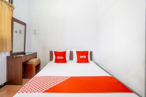 a bedroom with a bed with two red pillows at Hotel O Central Madiun Near Stasiun Kota Madiun in Madiun