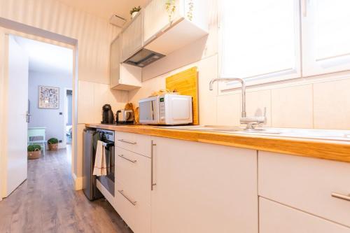 une cuisine avec des armoires blanches et un évier dans l'établissement Élégance et Bien-être dans notre T2 à Epernay, à Épernay