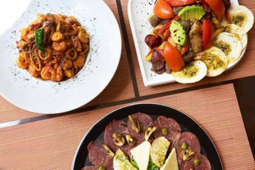 three plates of food on a wooden table at Renaissance Caracas La Castellana Hotel in Caracas