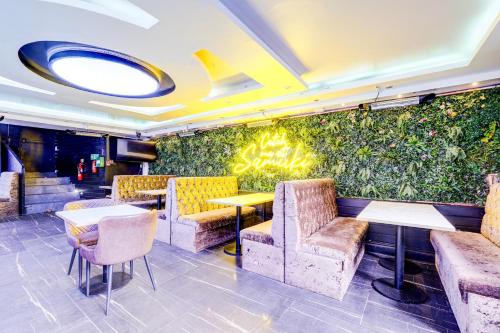 a restaurant with a green wall with tables and chairs at London Shelton Hotel, Finsbury Park in London