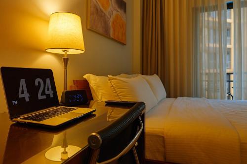 a hotel room with a laptop on a desk next to a bed at The Aston Executive Suite 2BR Balcony Near Mines View Baguio in Baguio