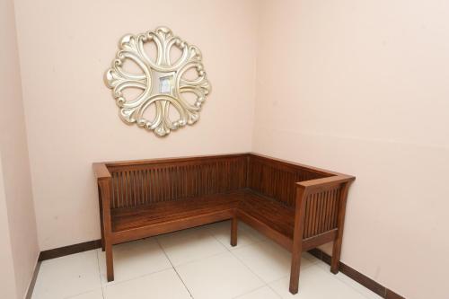 a wooden bench against a white wall with a mirror at Super OYO Capital O Deroyal Sentra Timur in Jakarta